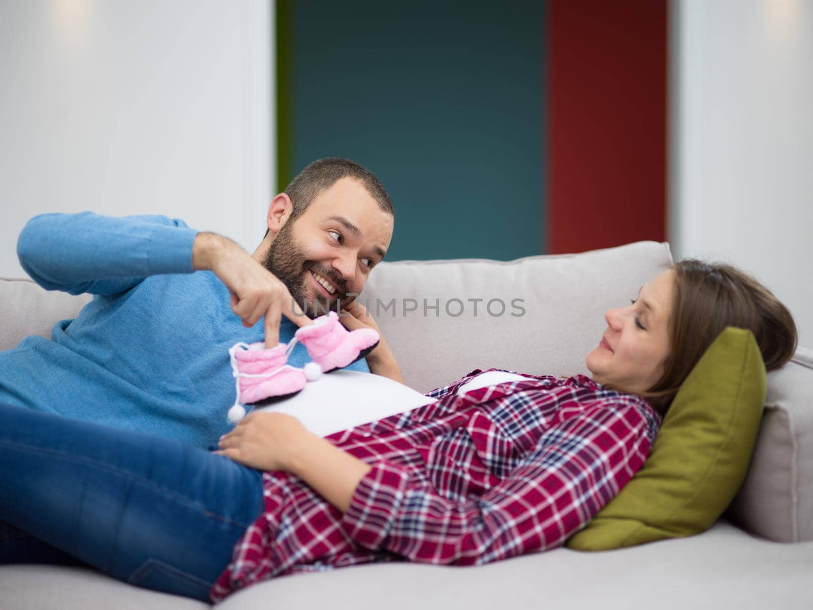 happy pregnant couple relaxing on sofa couch at home