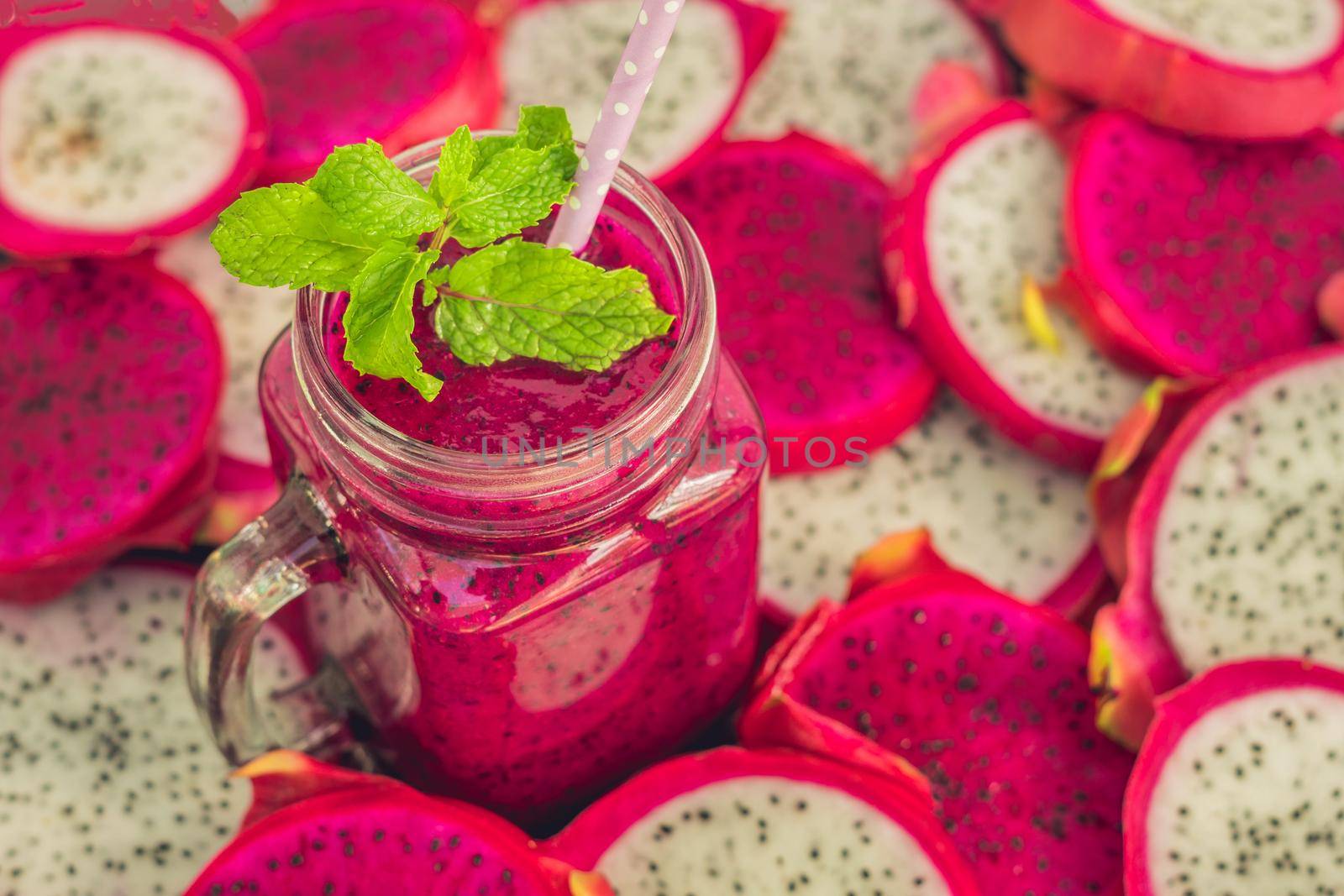 Smoothies of red organic dragon fruit and pieces of dragon fruit on an old wooden background.
