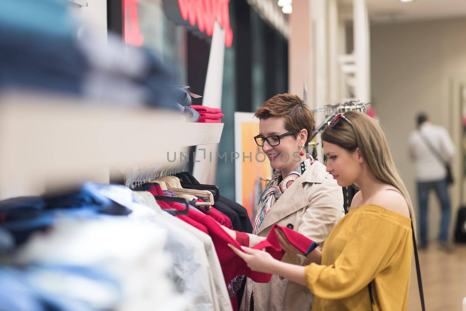 Two Girl-Friends On Shopping Walk On Shopping Centre With Bags And Choosing