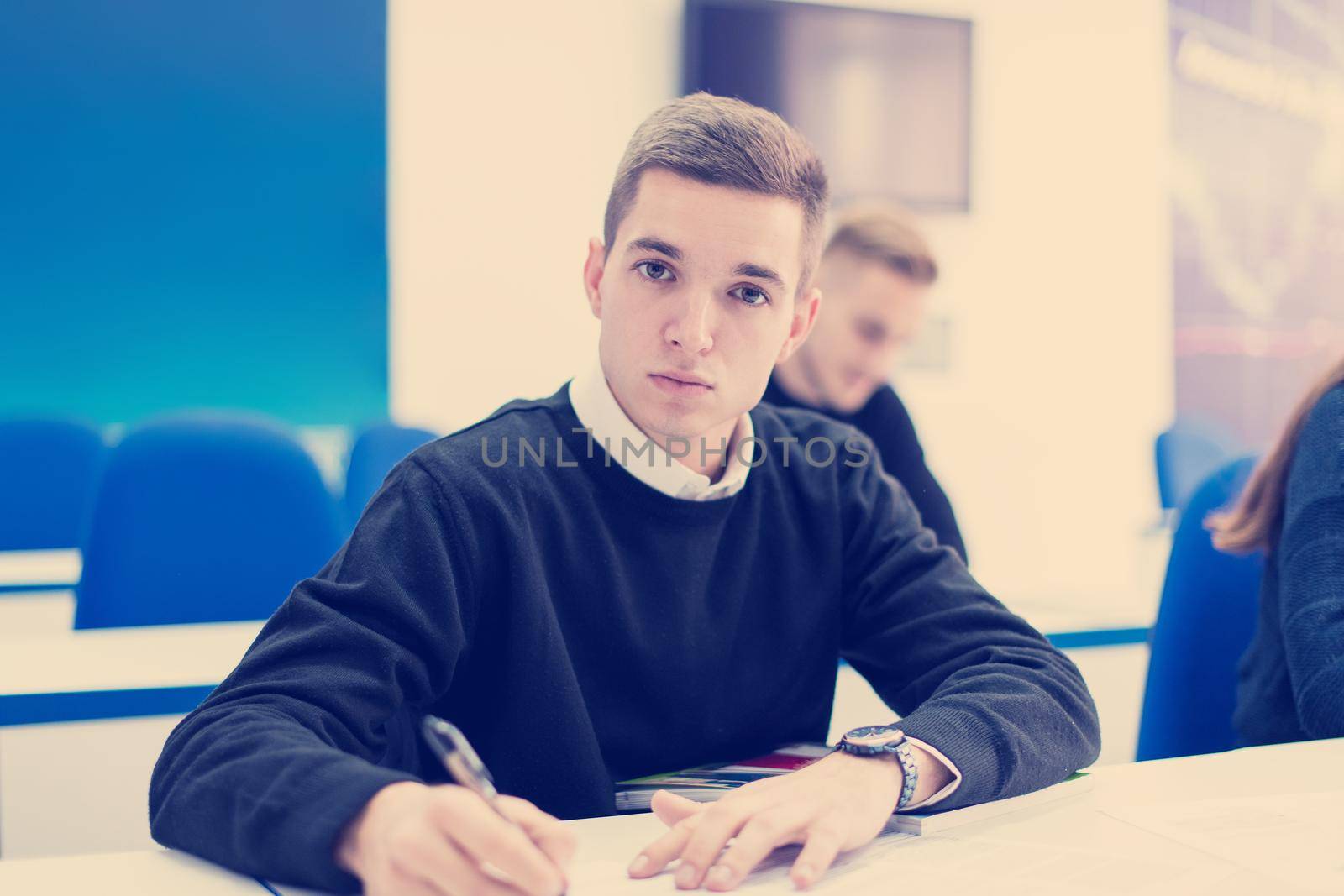 young male student writing notes in the classroom