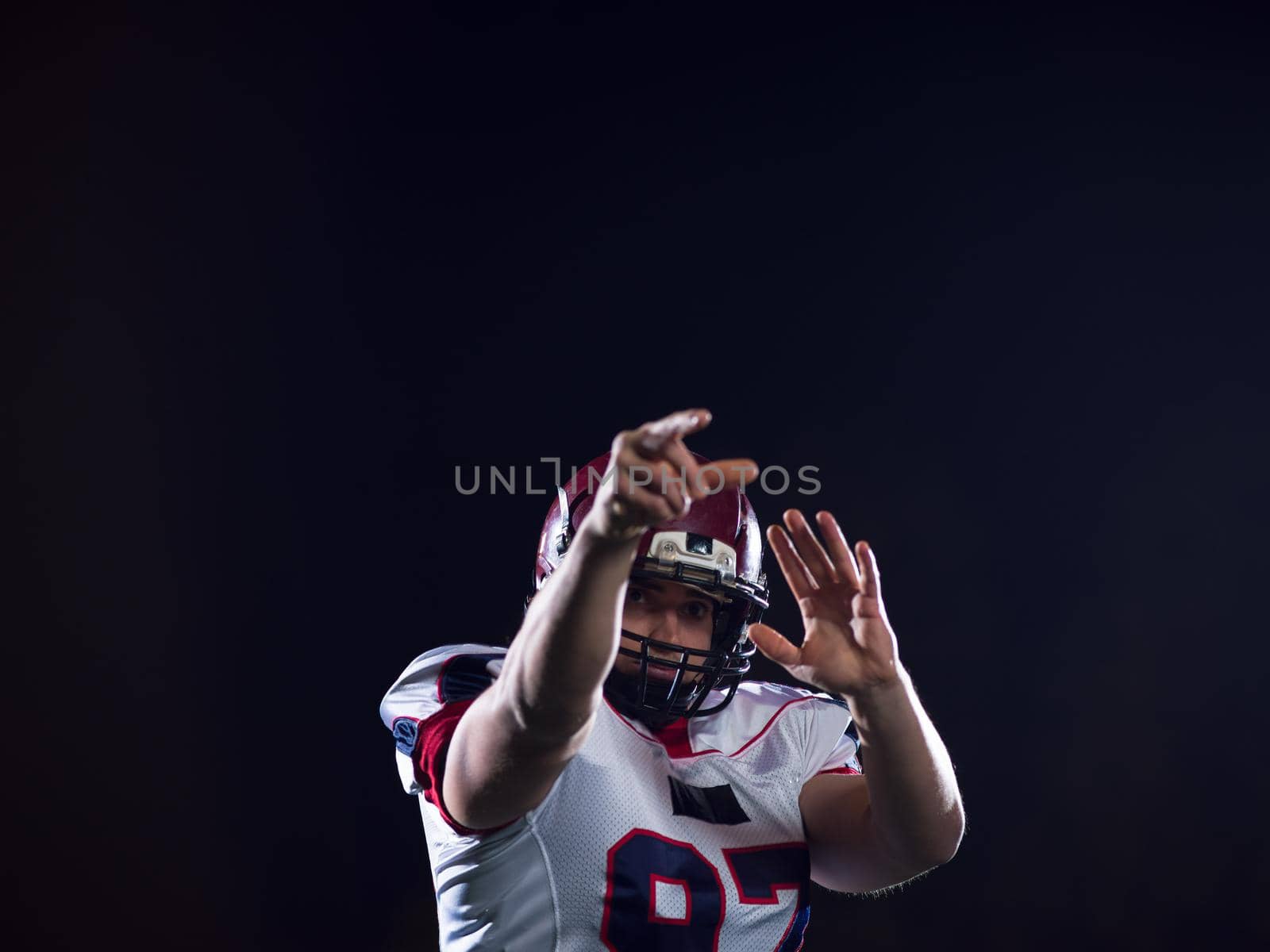 american football player throwing rugby ball against black background