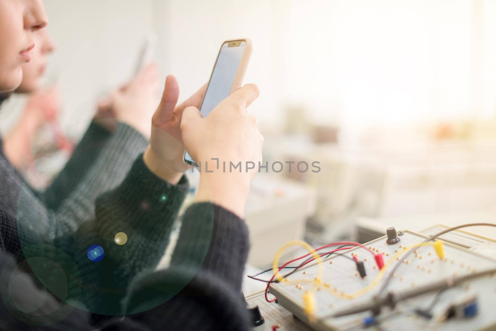 young female student using a mobile phone during the break in the electronics classroom
