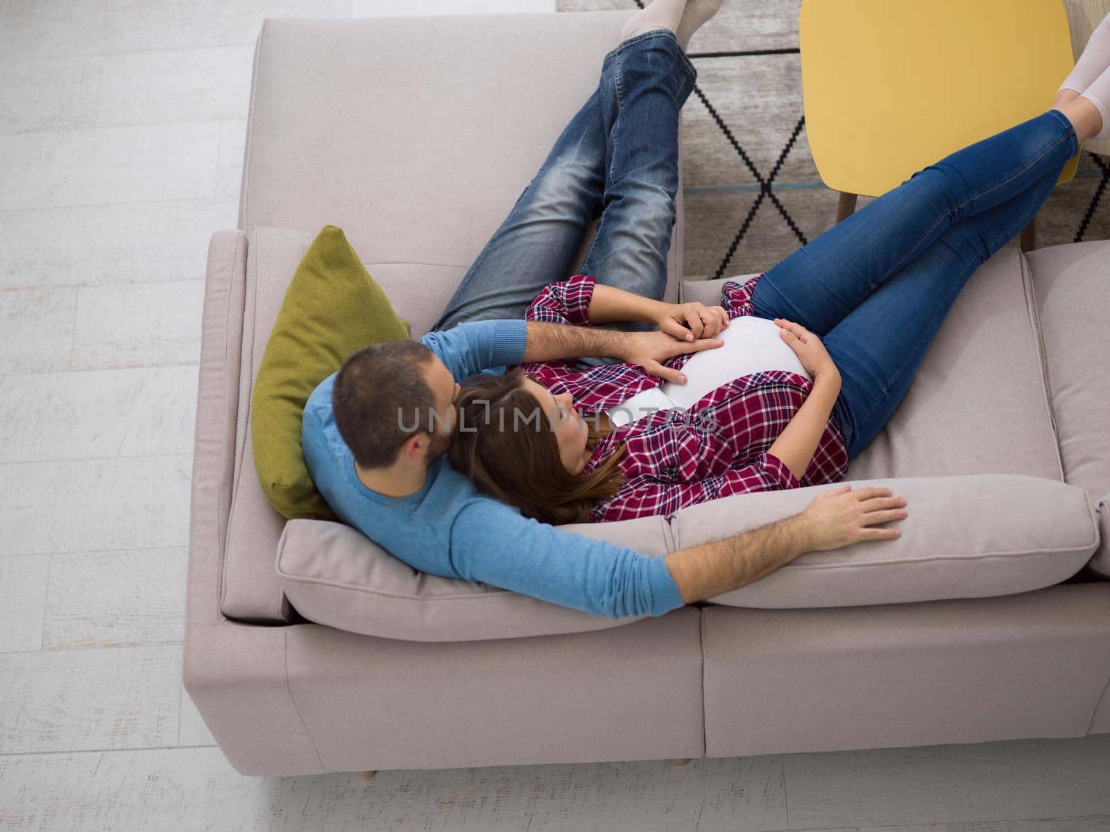 top view of happy pregnant couple relaxing on sofa couch at home