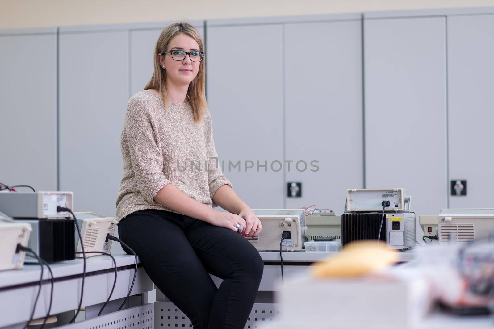 portrait of beautiful young female student sitting on the table at electronics laboratory classroom