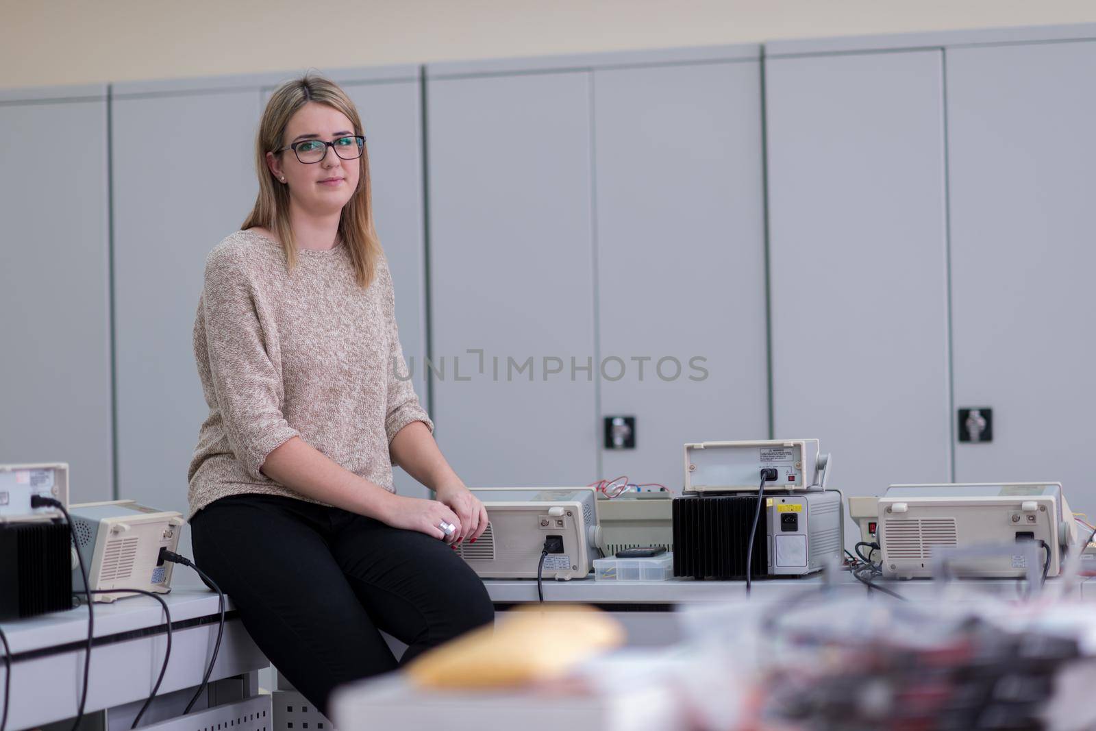 portrait of beautiful young female student sitting on the table at electronics laboratory classroom