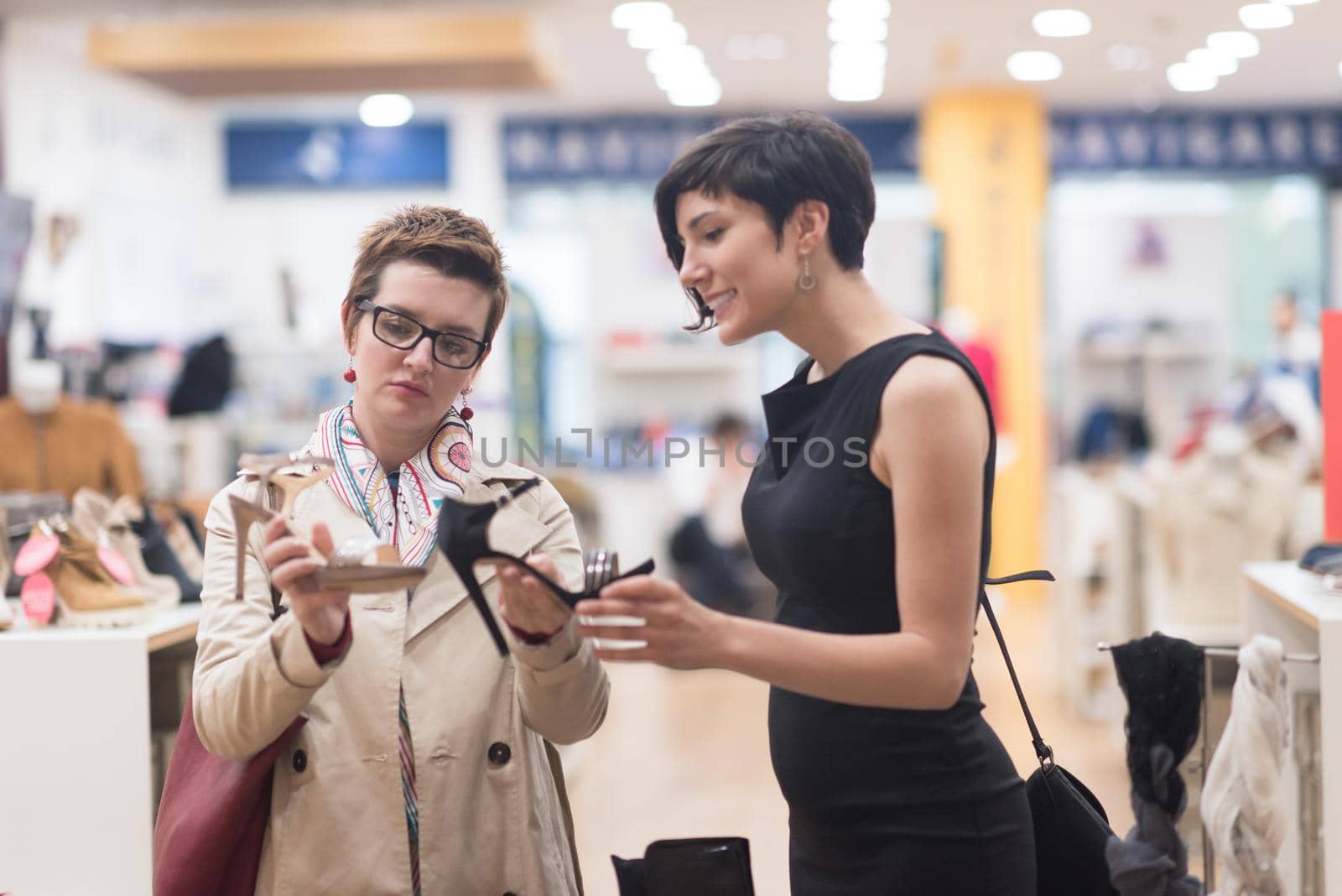 Two Girl-Friends On Shopping Walk On Shopping Centre With Bags And Choosing