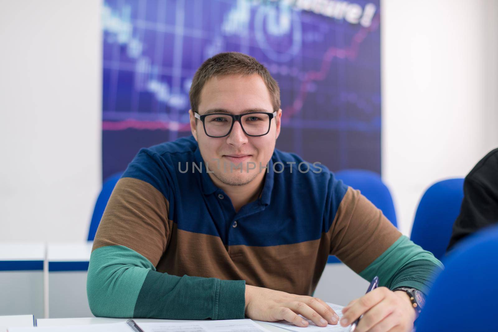 young male student writing notes in the classroom