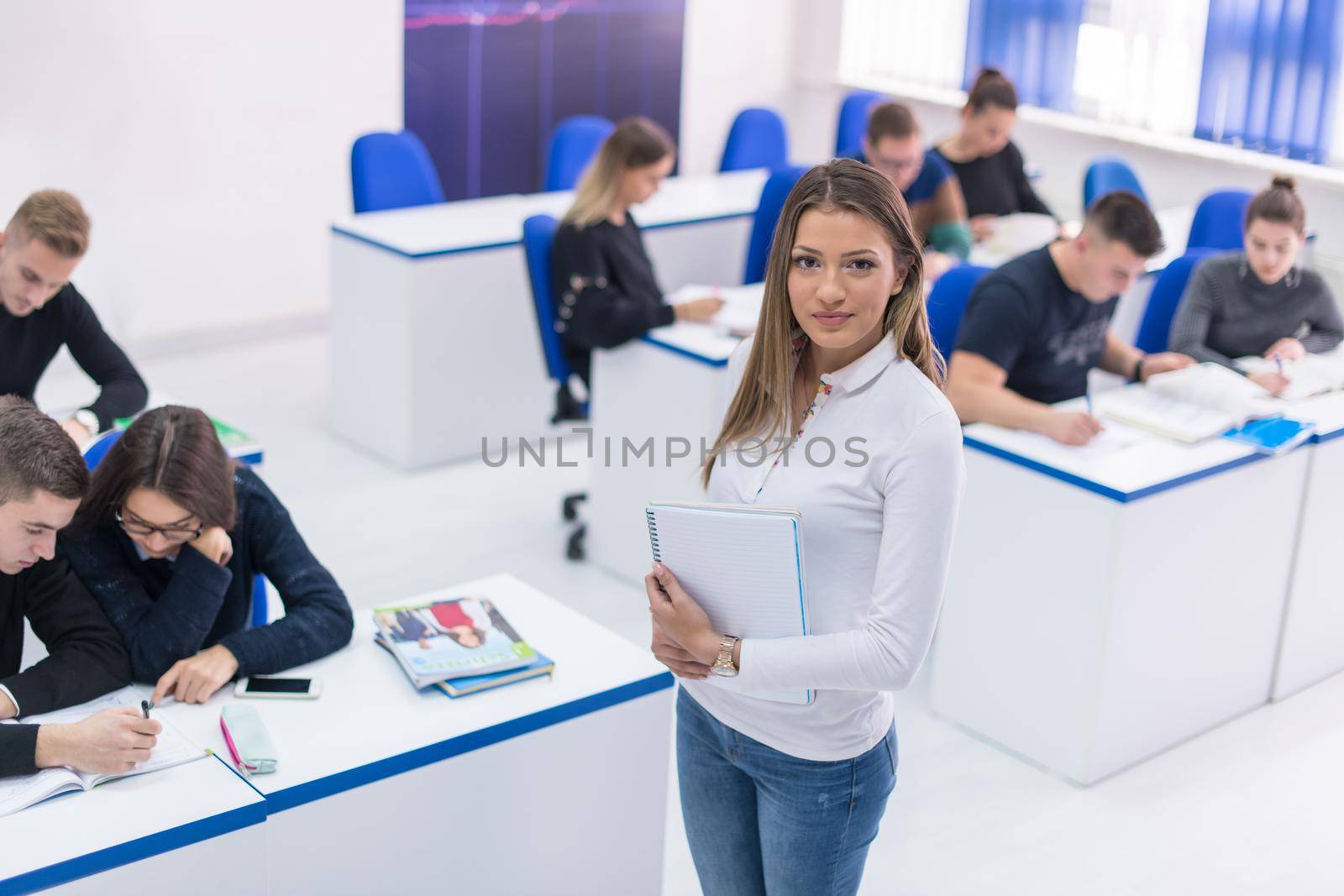 young beautiful female student with others writing notes in the classroom