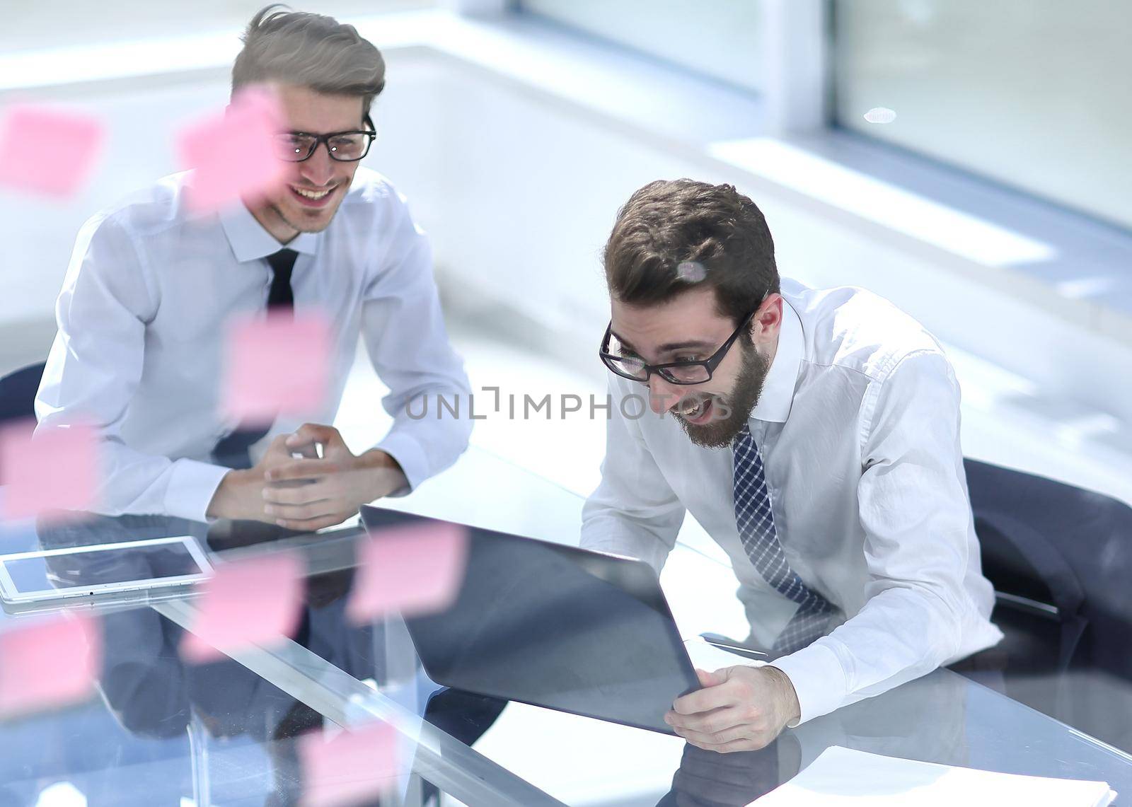 two happy employees reading a business document sitting at a Desk in a modern office