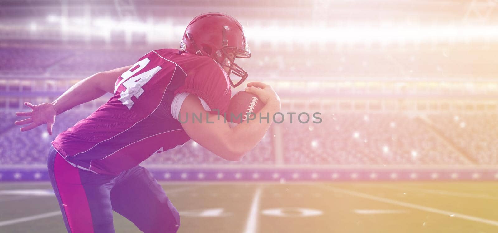 American football Player running with the ball isolated on big modern stadium field with lights and flares