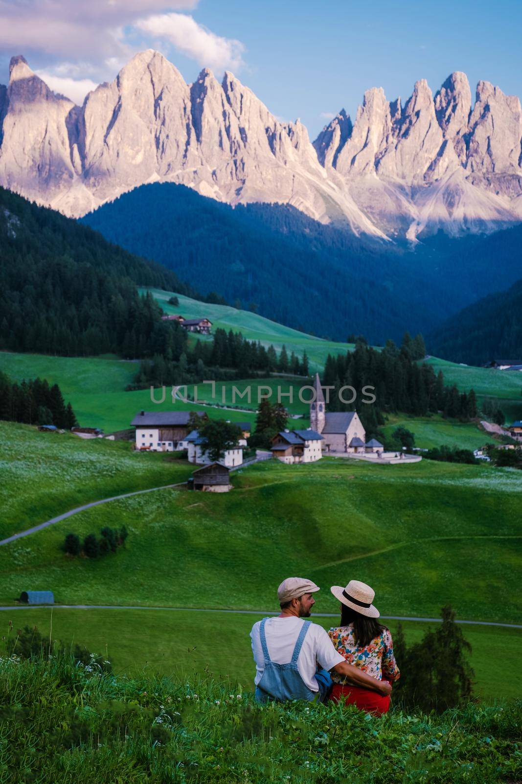 Santa Magdalena village in Val di Funes on the italian Dolomites. Autumnal view of the valley with colorful trees and Odle mountain group. Italy, man and woman on vacation, hiking in the mountains