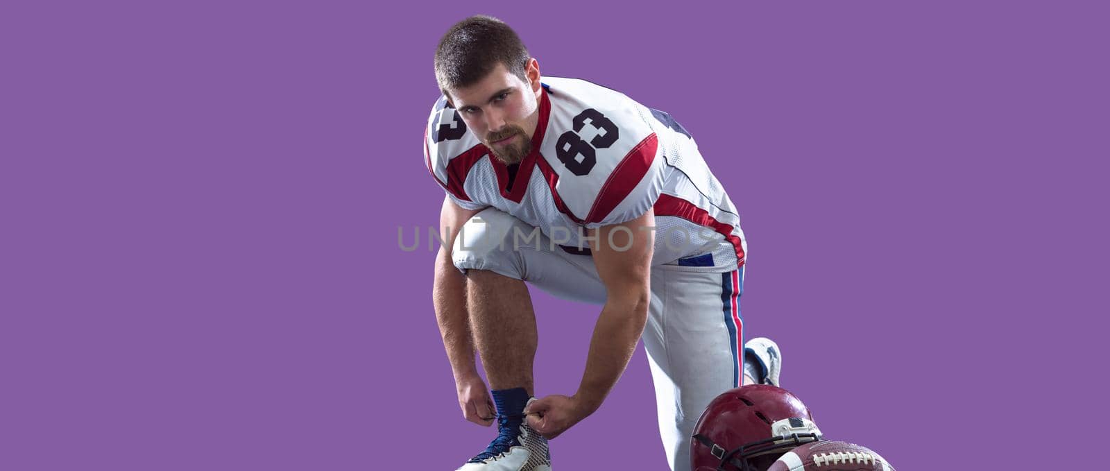 portrait of confident American football player isolated on colorful background