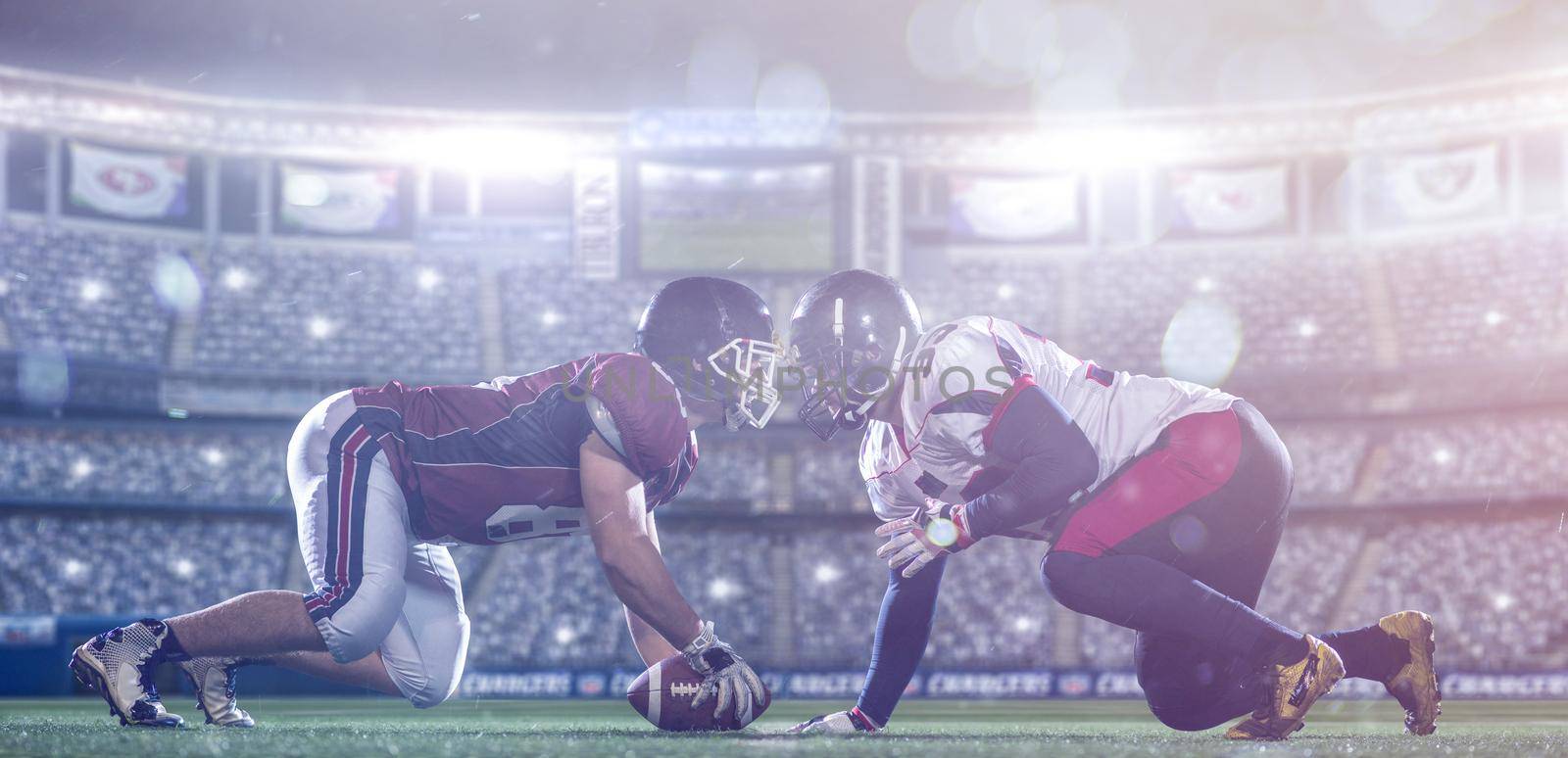 american football players are ready to start a match on modern field at night