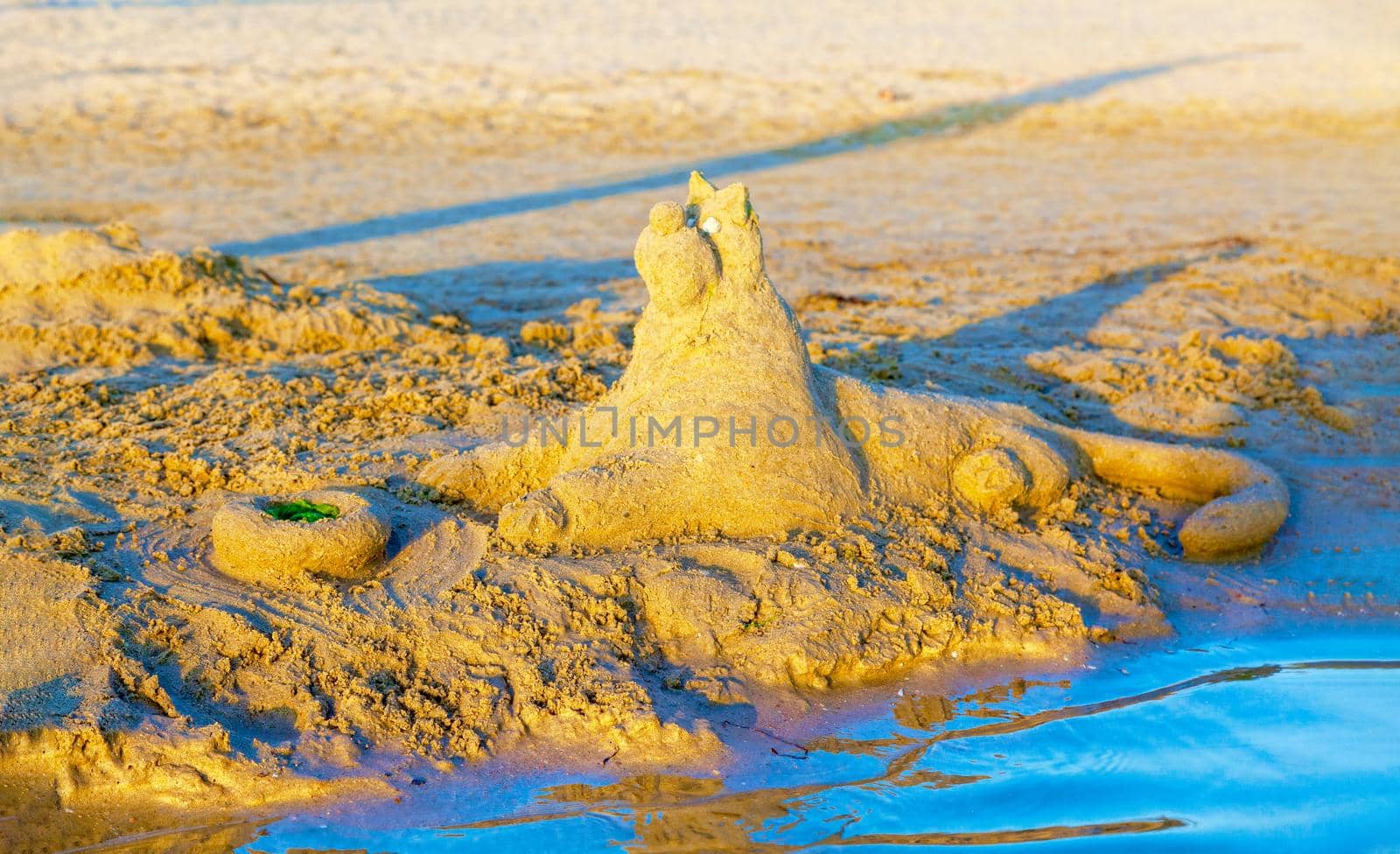 Beautiful sand castle illuminated by the morning sun on the beach of the tropical sea. The concept of a family vacation at sea.