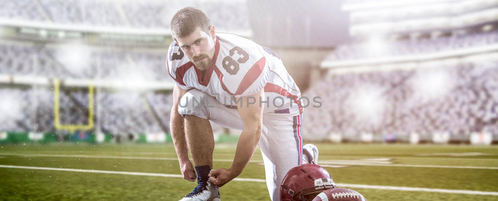 American Football Player preparing for match on big modern stadium field with lights and flares