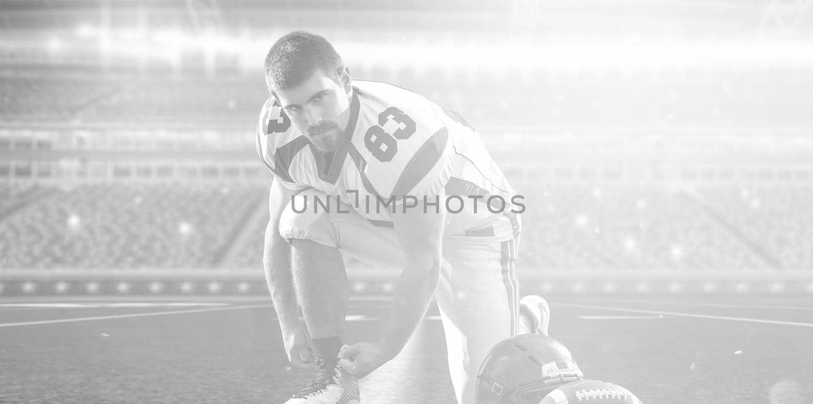 American Football Player preparing for match on big modern stadium field with lights and flares