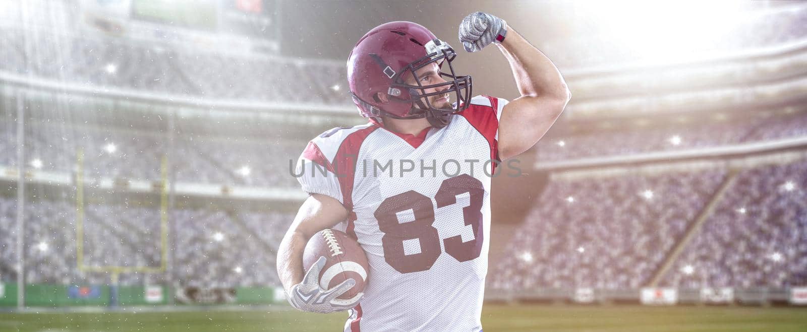 american football player celebrating touchdown on big modern stadium field with lights and flares