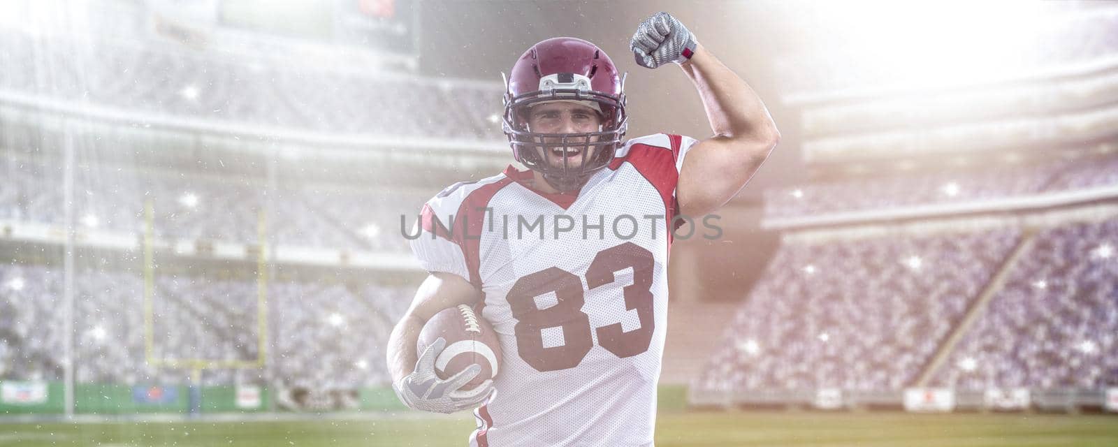 american football player celebrating touchdown on big modern stadium field with lights and flares