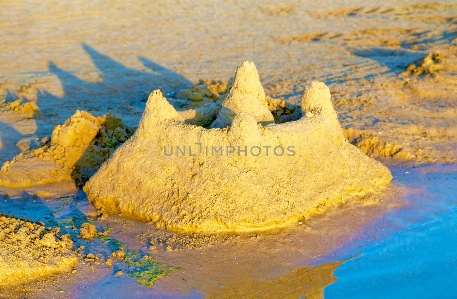 Beautiful sand castle illuminated by the morning sun on the beach of the tropical sea. The concept of a family vacation at sea.