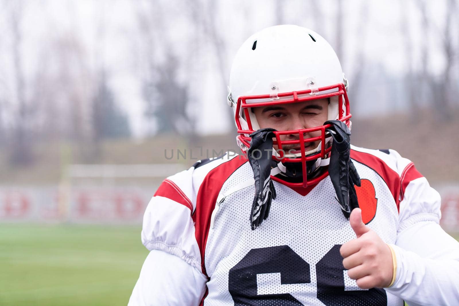 portrait of young confident American football player standing on the field during training