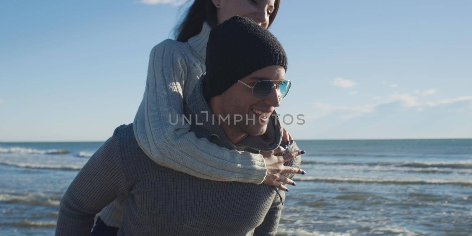 Men Giving Piggy Back Rides At Sunset By The Sea, autumn time