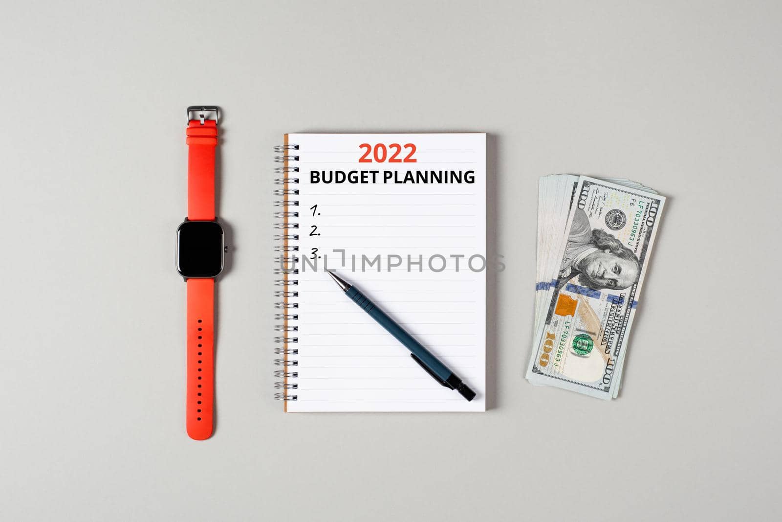 2022 budget planning banner with copy space. Notepad, pen, stack of money and a cup of black coffee isolated on gray background. Notepad with copy space. Office, business, discreet style