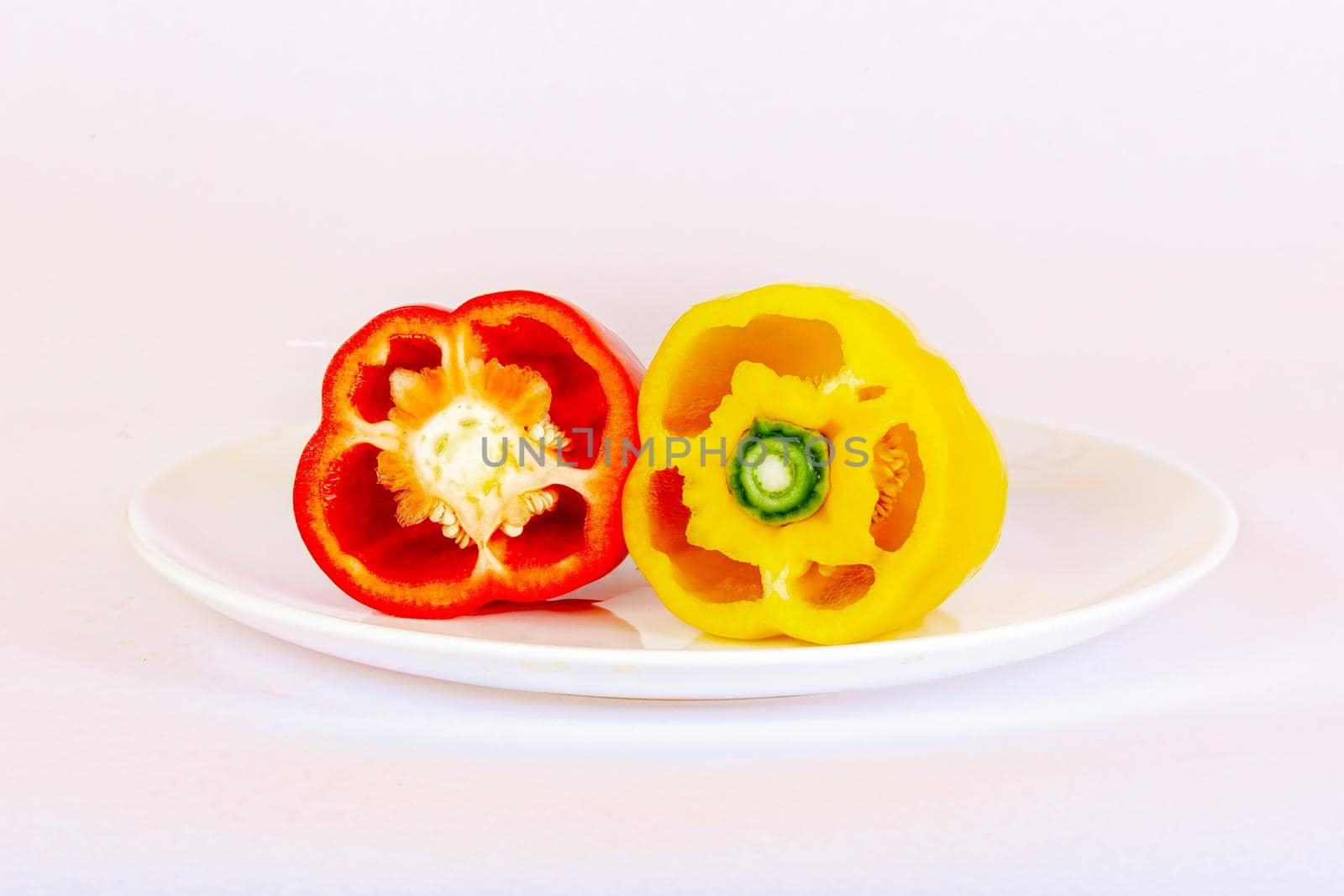 Bulgarian pepper red and sliced yellow lies on a white plate. The concept of a healthy diet.