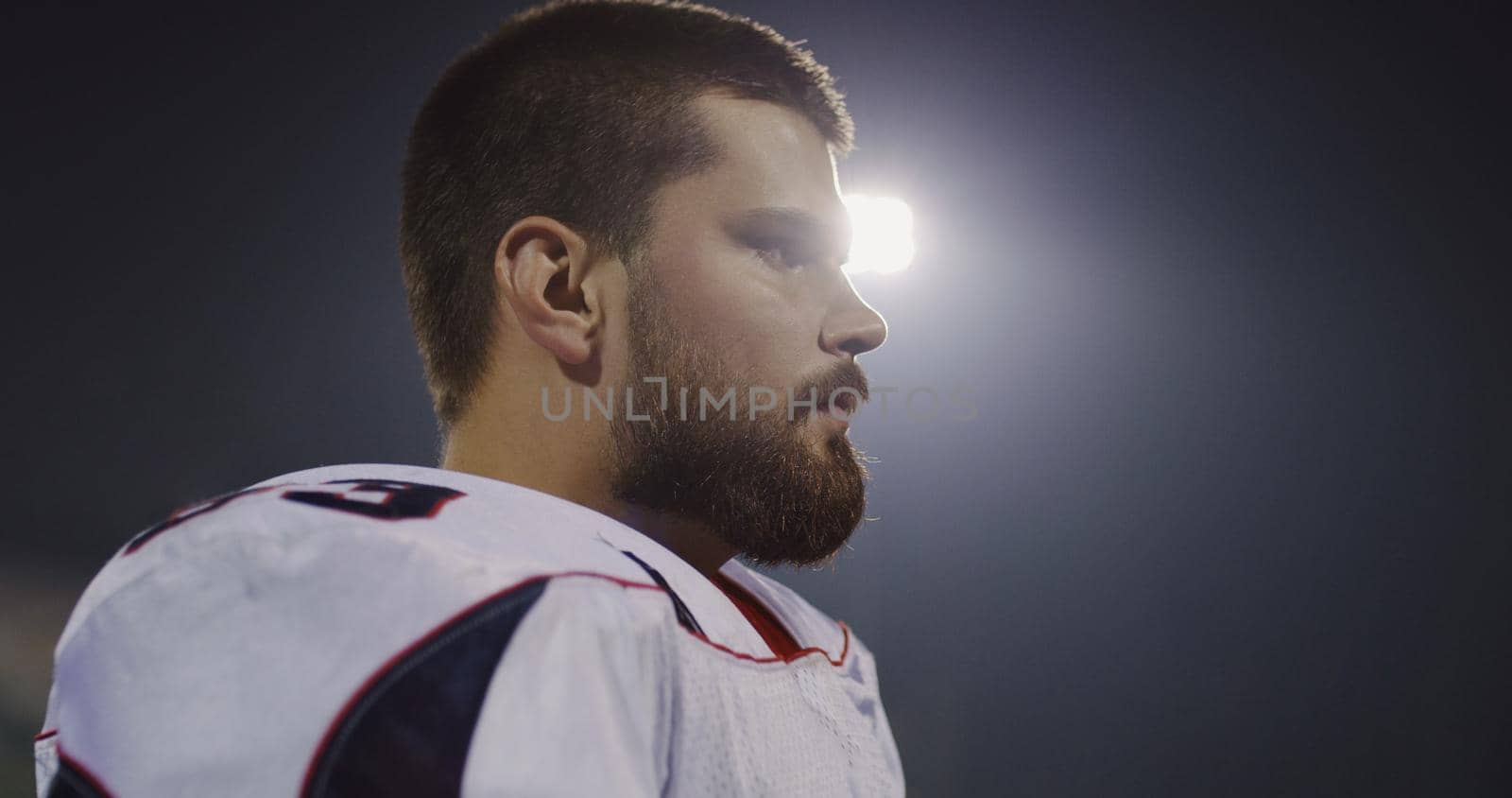 portrait of young confident American football player  standing on field at night