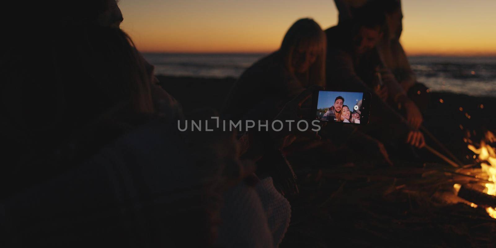 Couple taking photos beside campfire on beach by dotshock