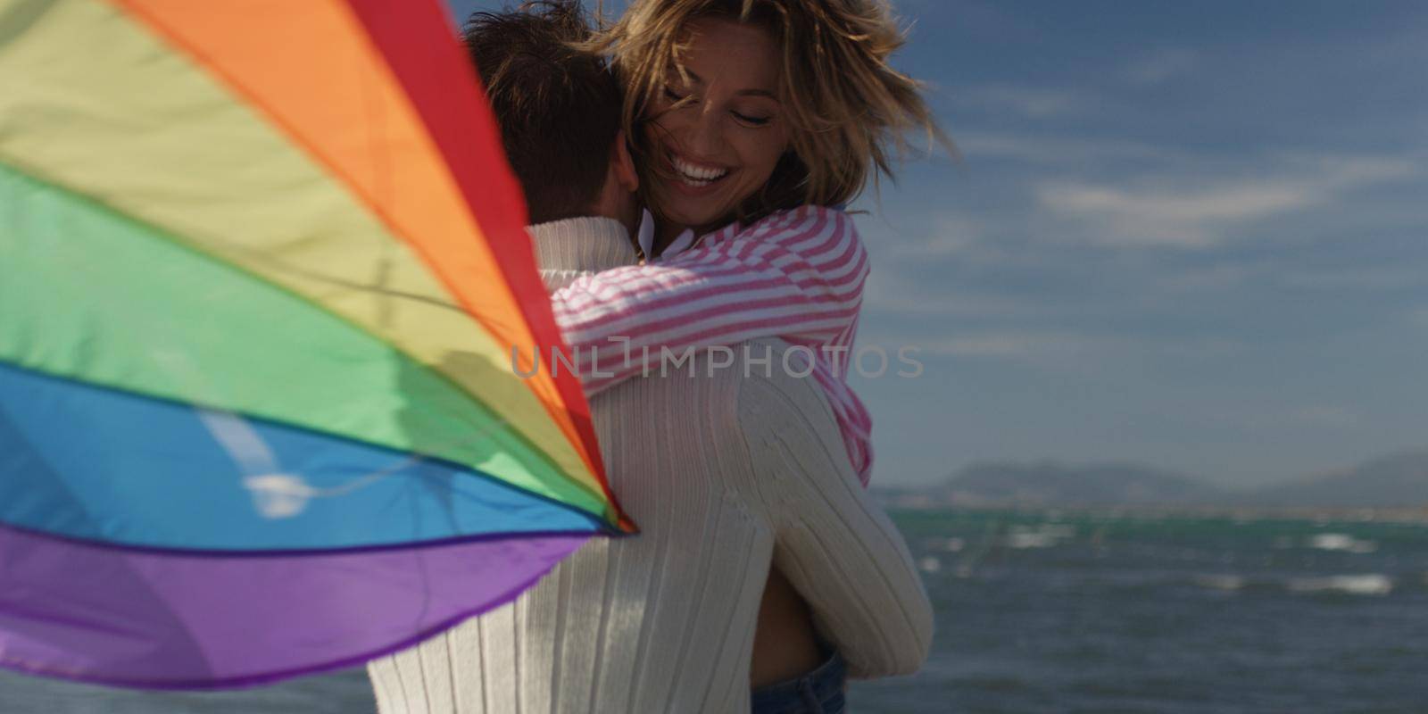 Happy couple having fun with kite on beach by dotshock