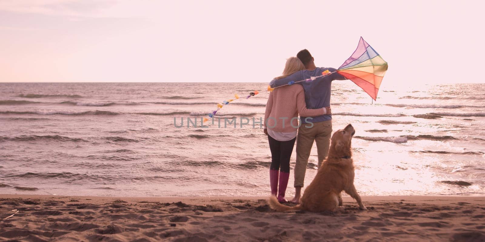 couple with dog having fun on beach on autmun day by dotshock