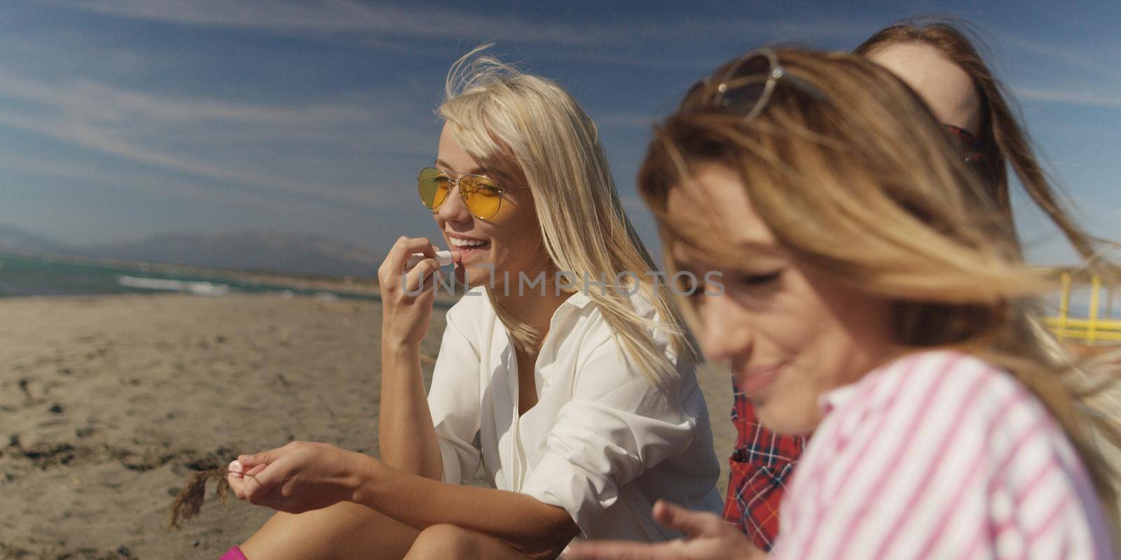 Group of girlfriends having fun on beach during autumn day by dotshock