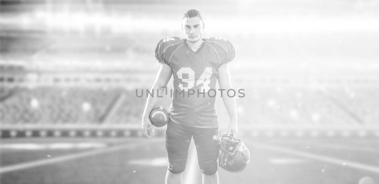 American Football Player isolated on big modern stadium field with lights and flares