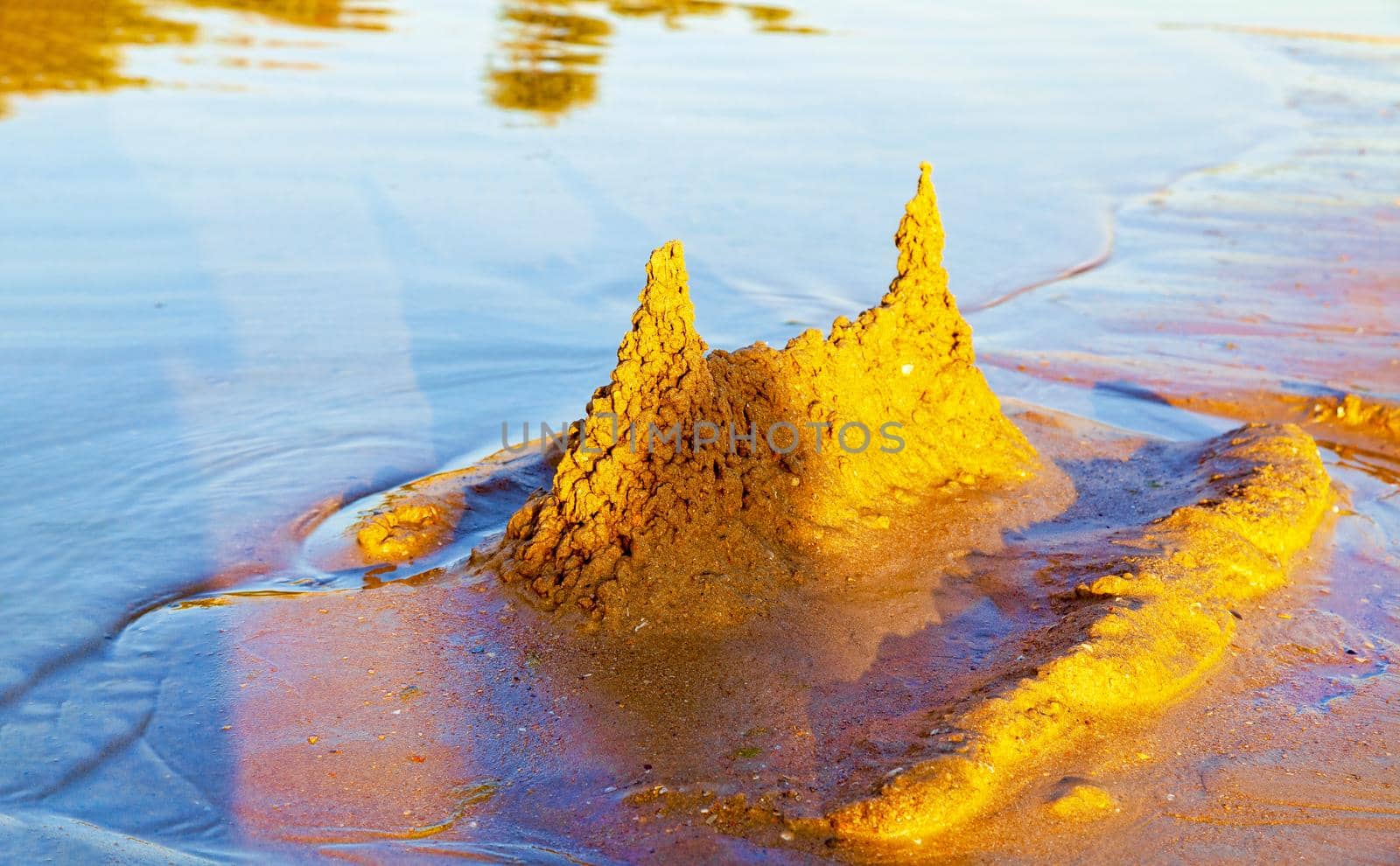 Beautiful sand castle illuminated by the morning sun on the beach of the tropical sea. The concept of a family vacation at sea.