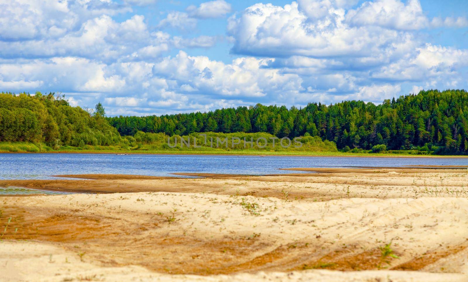 Wild sandy beach near the river on a fine summer day. Only blue sky, sand and a quiet river. Russia, Kostroma region, Kozionikha village. The concept of tourism, native land.