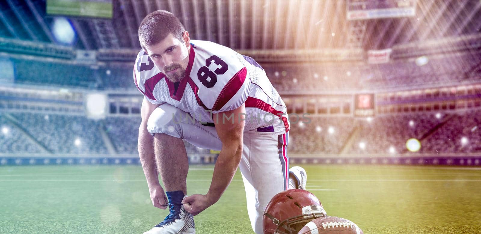 American Football Player preparing for match on big modern stadium field with lights and flares