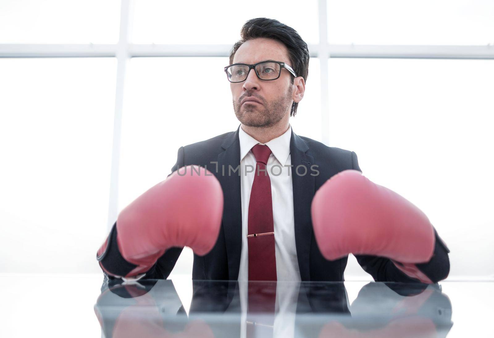 confident businessman in Boxing gloves sitting at the office Desk.business concept