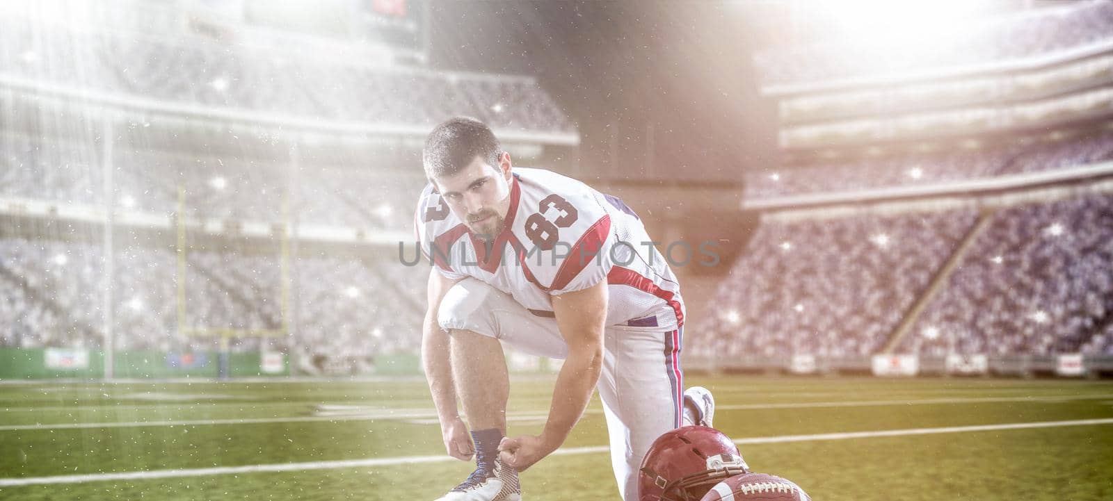 American Football Player preparing for match on big modern stadium field with lights and flares