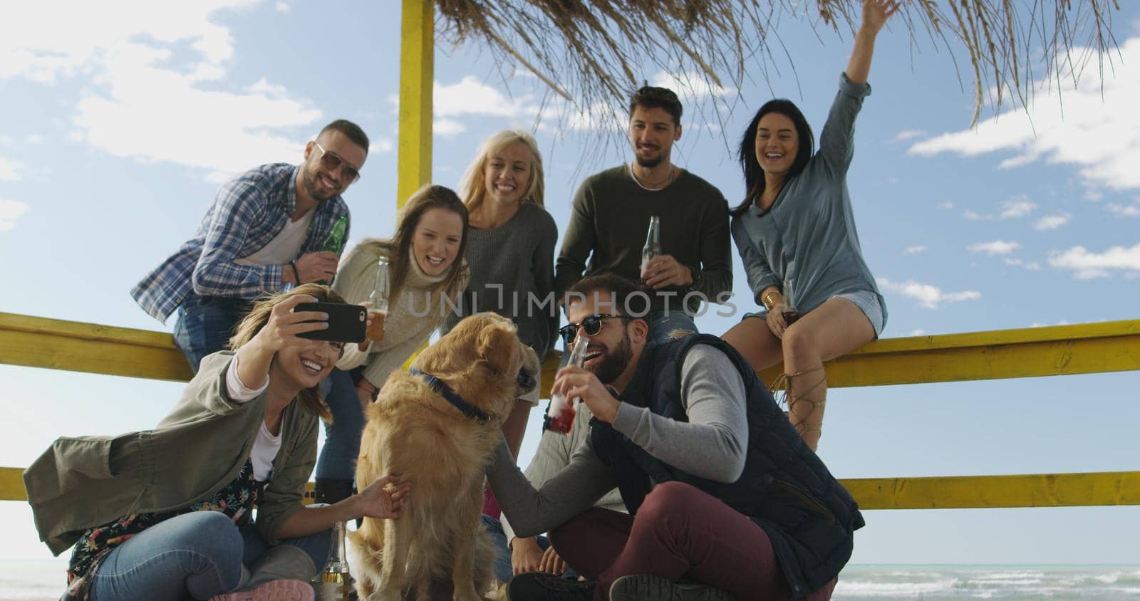 Group of friends having fun on autumn day at beach by dotshock