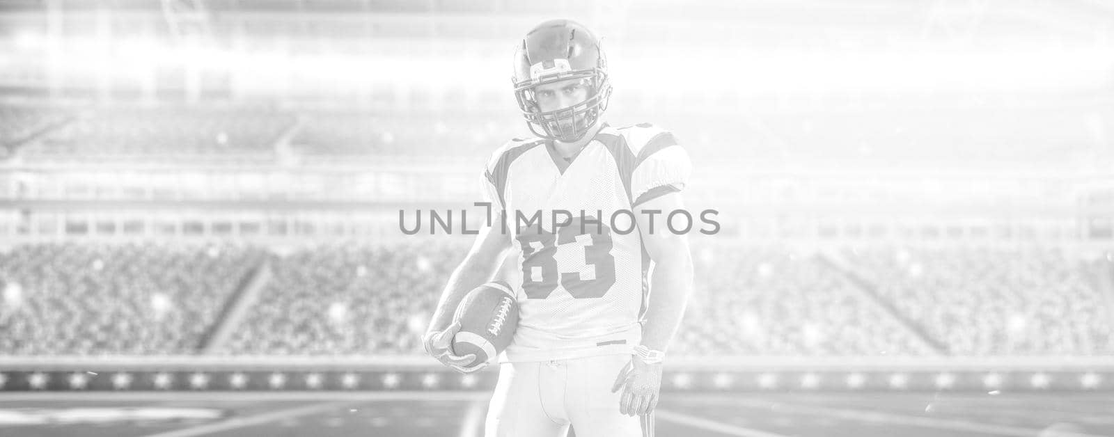 American Football Player isolated on big modern stadium field with lights and flares