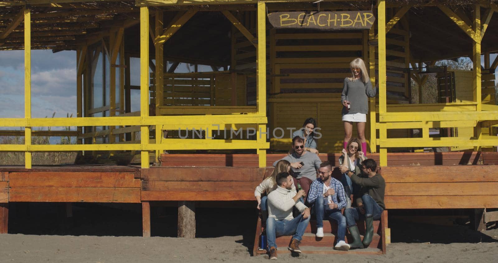 Group of friends having fun on autumn day at beach by dotshock