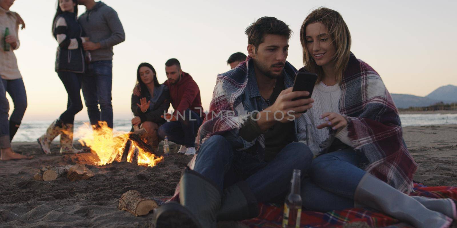 Couple enjoying bonfire with friends on beach by dotshock