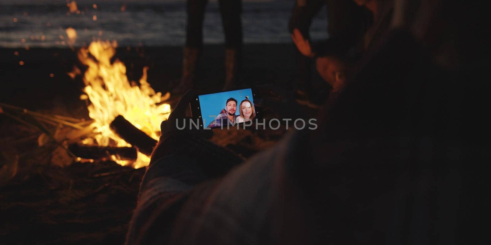 Couple taking photos beside campfire on beach by dotshock