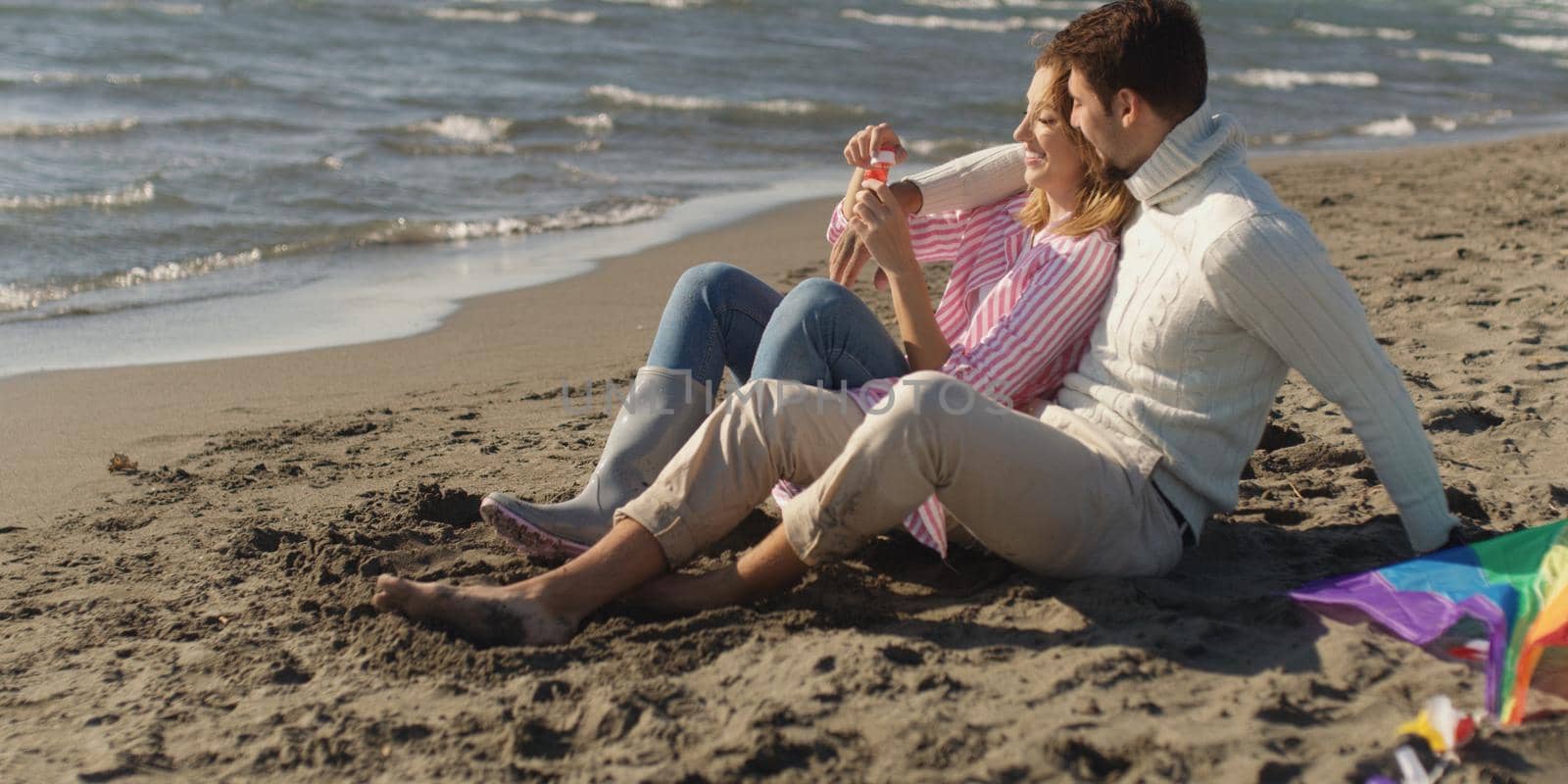 Young Couple having fun and Playing With A Kite On The Beach at autumn day