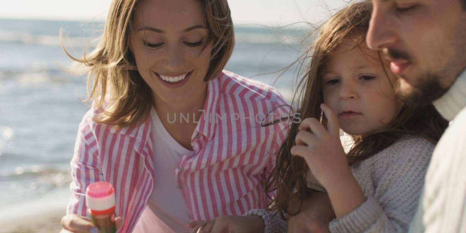 Family with kids resting and having fun at beach during autumn day