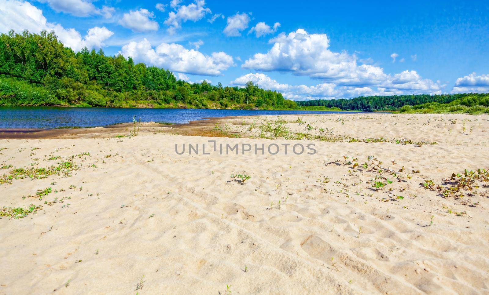Wild sandy beach near the river on a fine summer day. Only blue sky, sand and a quiet river. Russia, Kostroma region, Kozionikha village. The concept of tourism, native land.