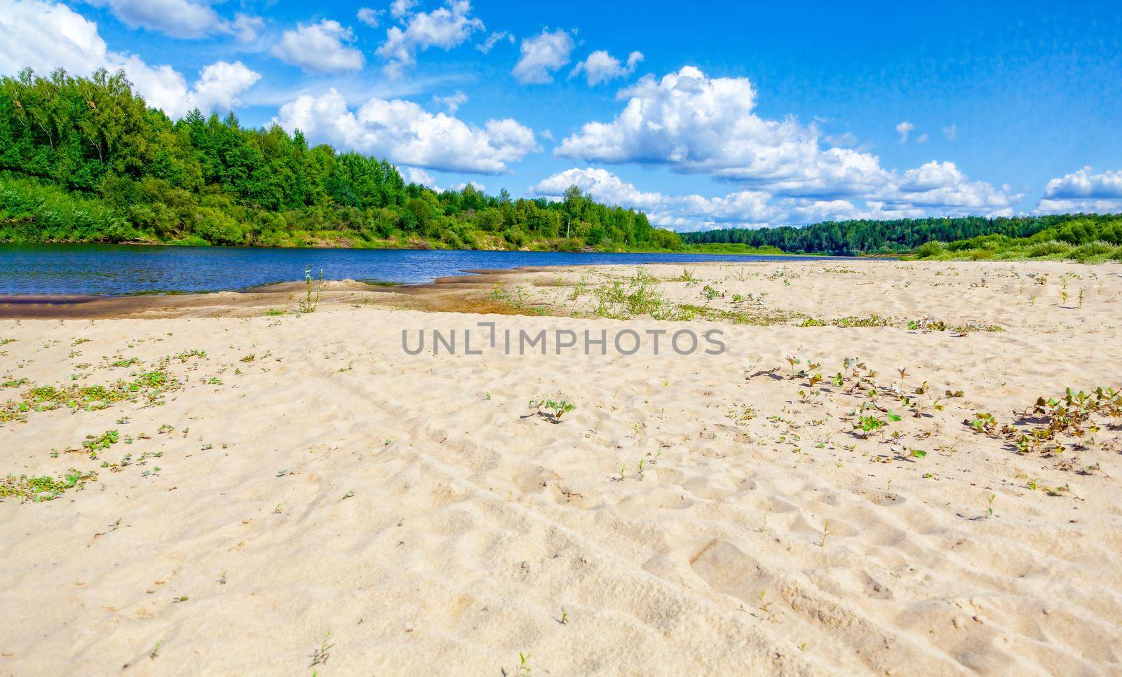 Wild sandy beach near the river on a fine summer day. Only blue sky, sand and a quiet river. Russia, Kostroma region, Kozionikha village. The concept of tourism, native land.