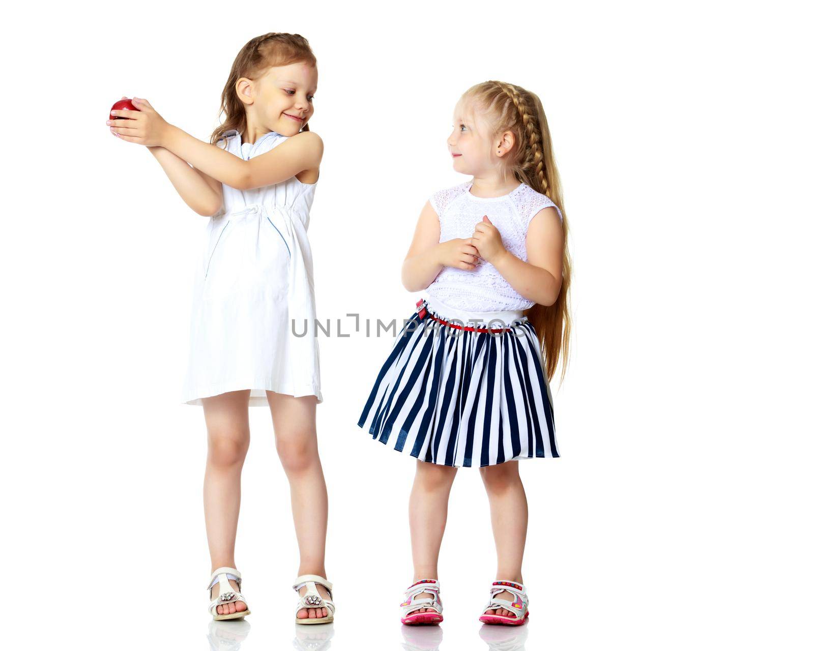 Two cute little girls with apples, in the studio on a white background. Concept of happy childhood, healthy eating. Isolated.