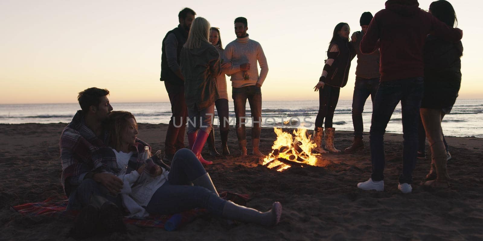 Friends having fun at beach on autumn day by dotshock