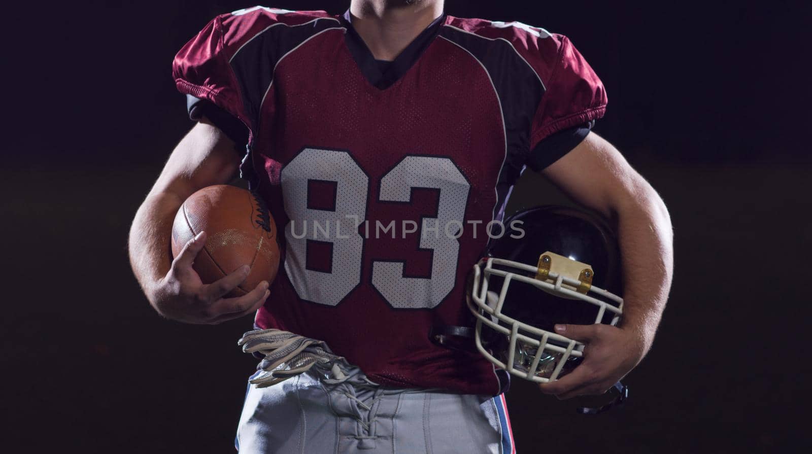 portrait of young confident American football player on field at night